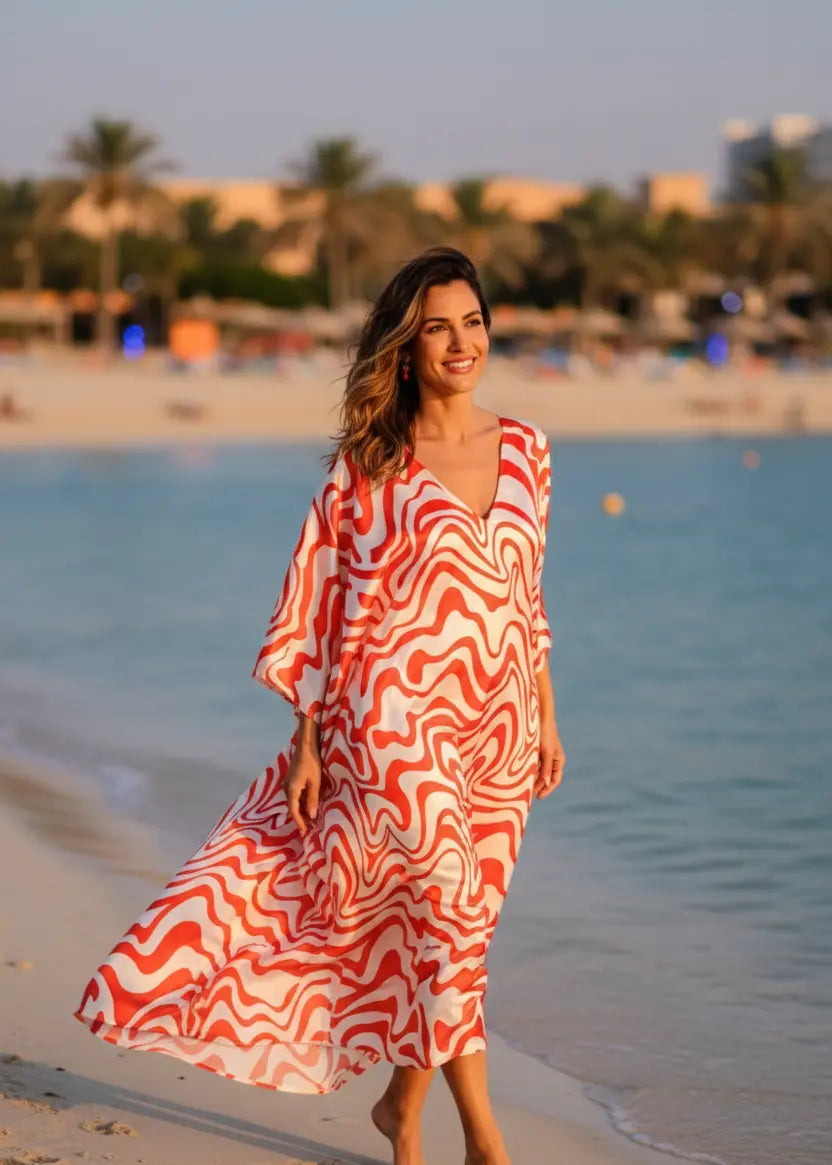 woman in Vicharan CRIMSON Orange caftan walking alongsie beach at sunset