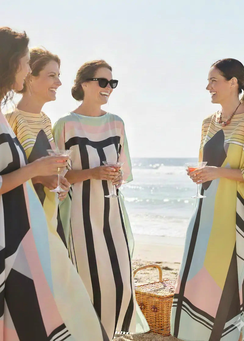 Four women in stylish Vicharan caftans standing on a beach with a clear sky forbachelor party.